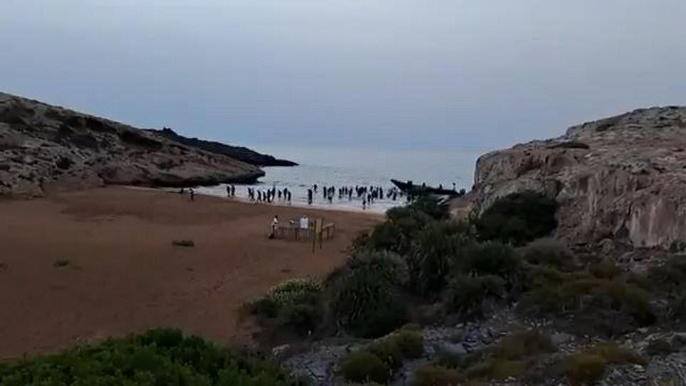 Moment dozens of cheering migrants charge up Spanish beach after being dropped off by speedboat 'taxi'