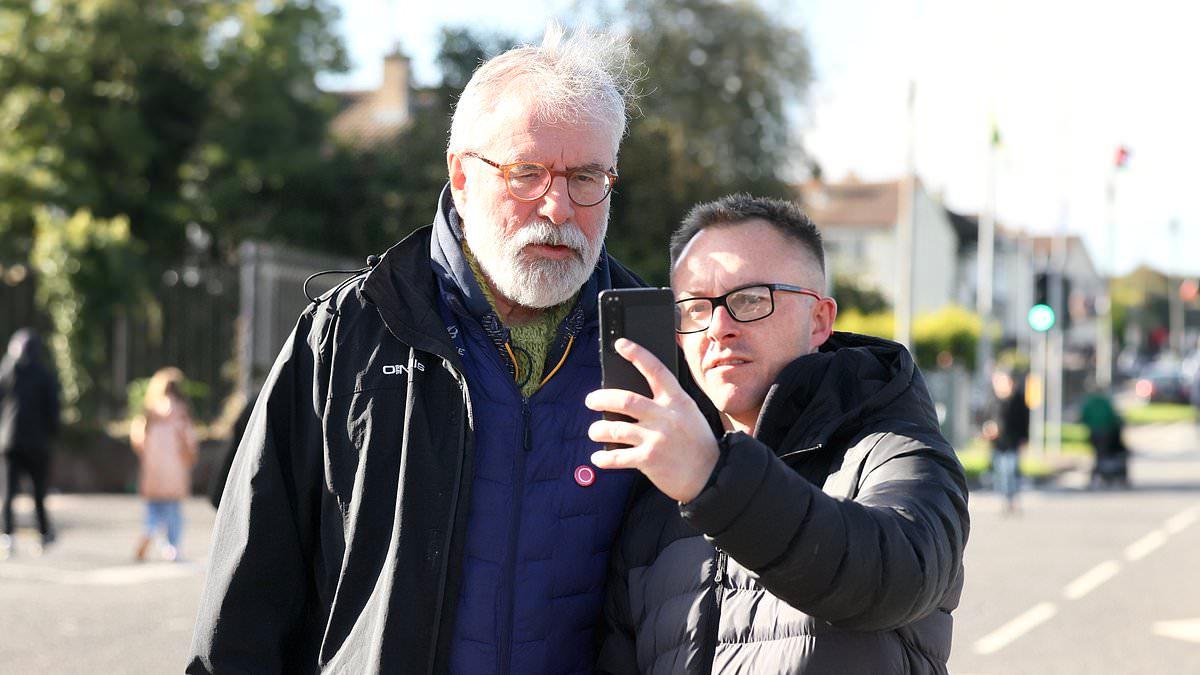 Former Sinn Fein leader Gerry Adams arrives at Orange Order protest after DUP accuses the party of 'breaking the law' by joining blockade - as demonstrator hurls bottle at police car